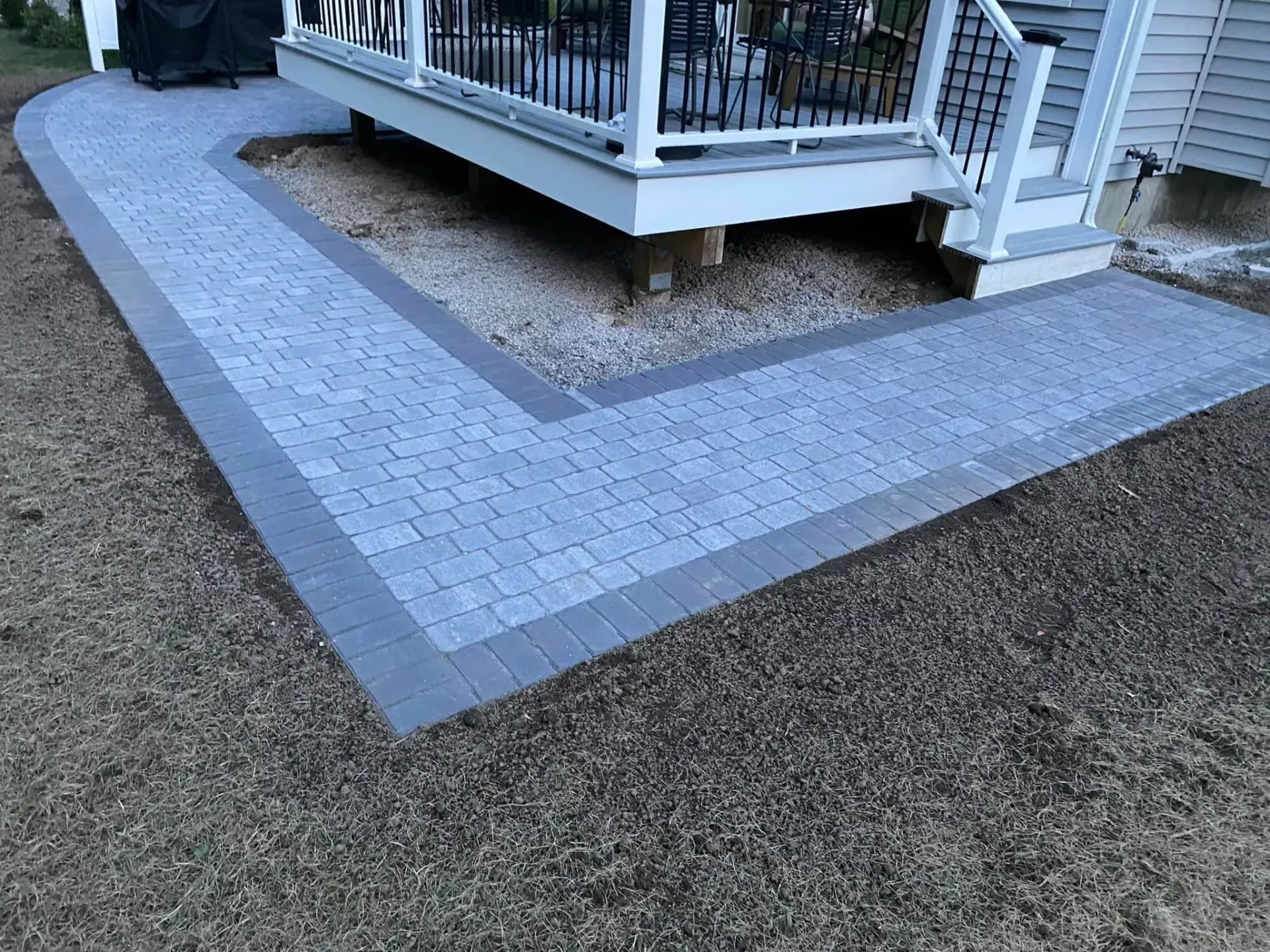 A walkway leading to a deck with stairs leading up to it.