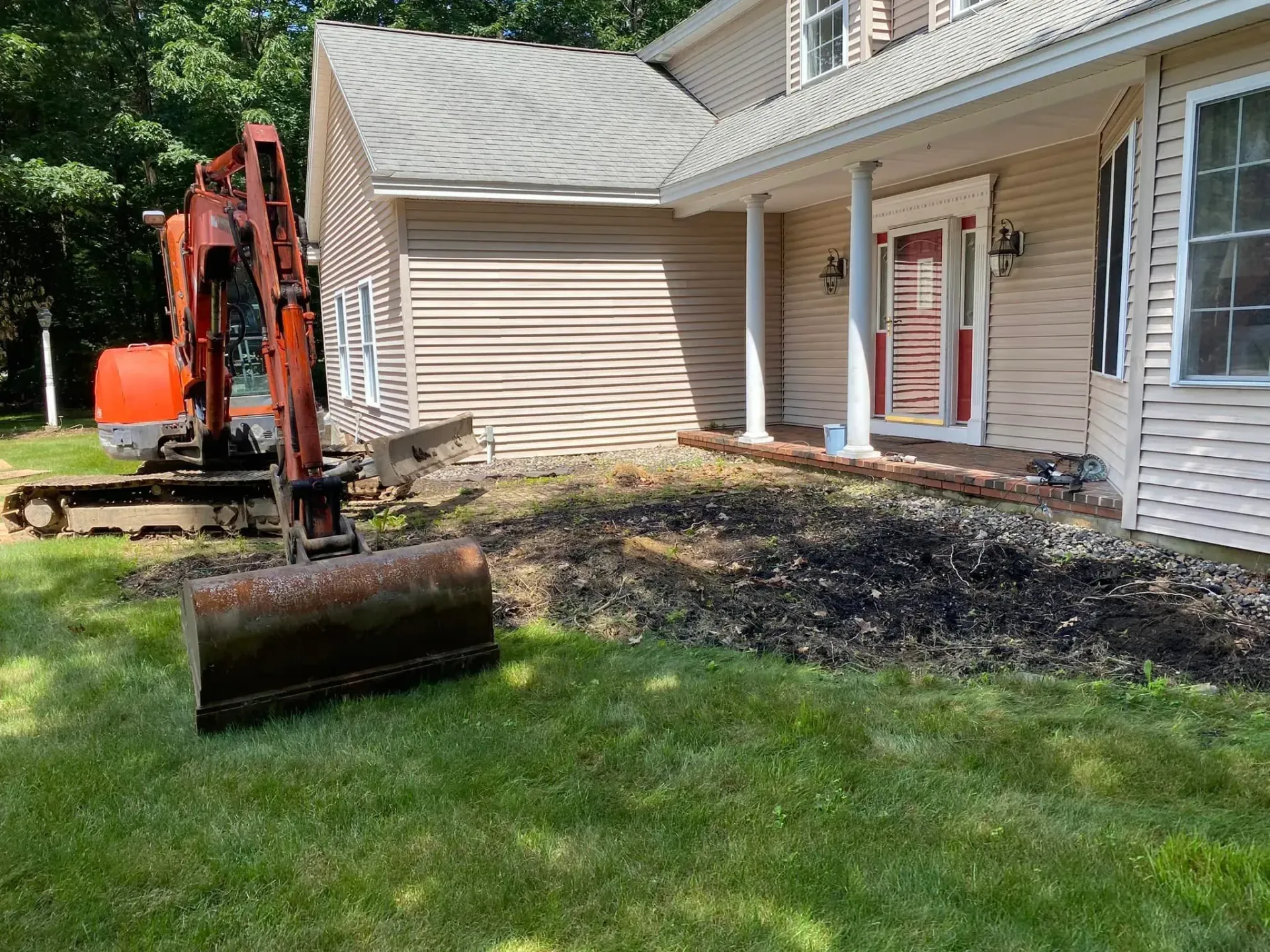 An excavator is sitting in front of a house.