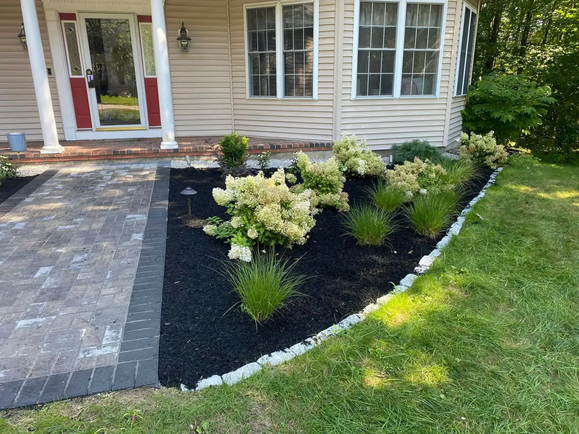 A house with a patio and a garden in front of it.