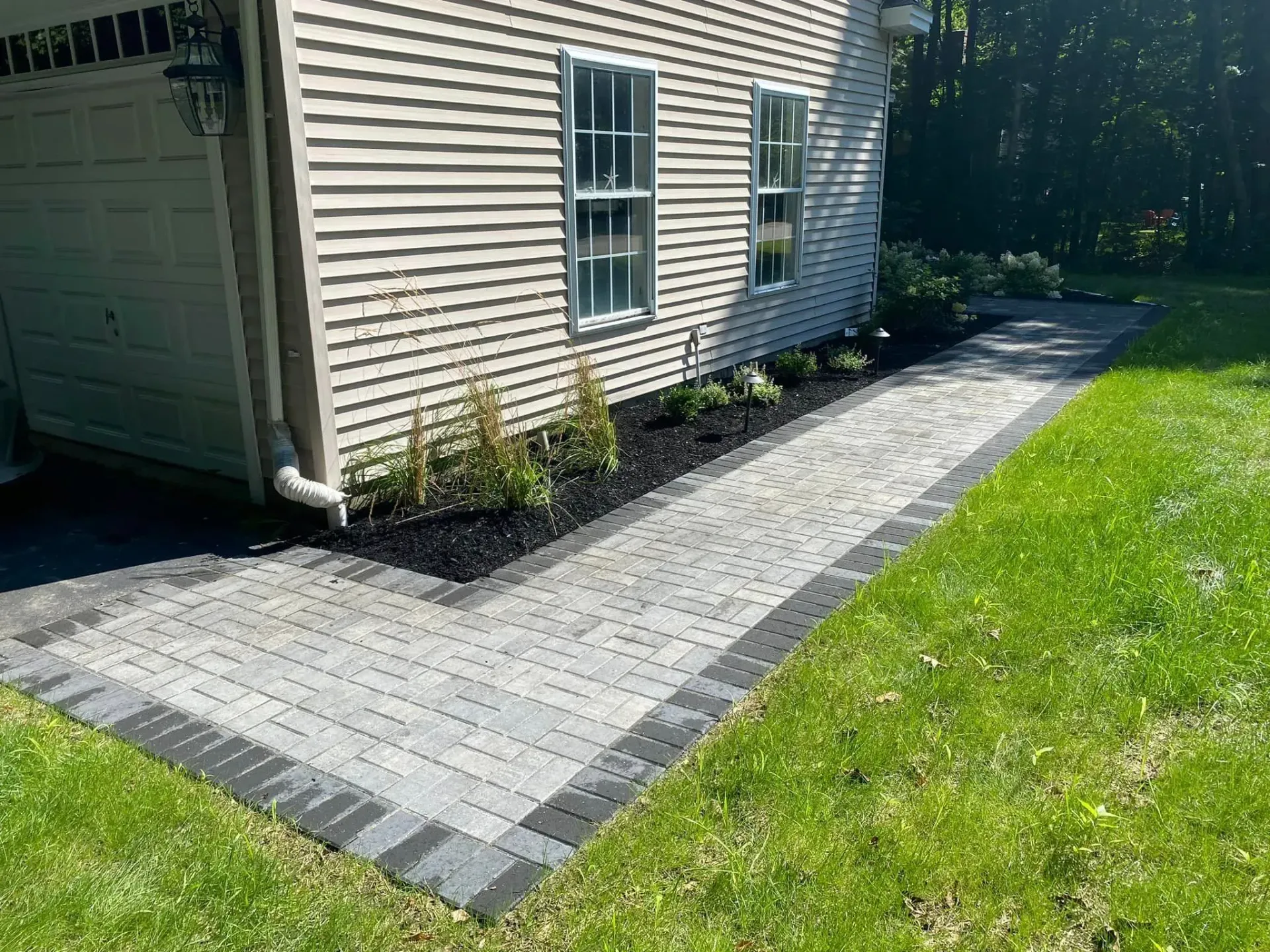 A brick walkway leading to a house with a garage.