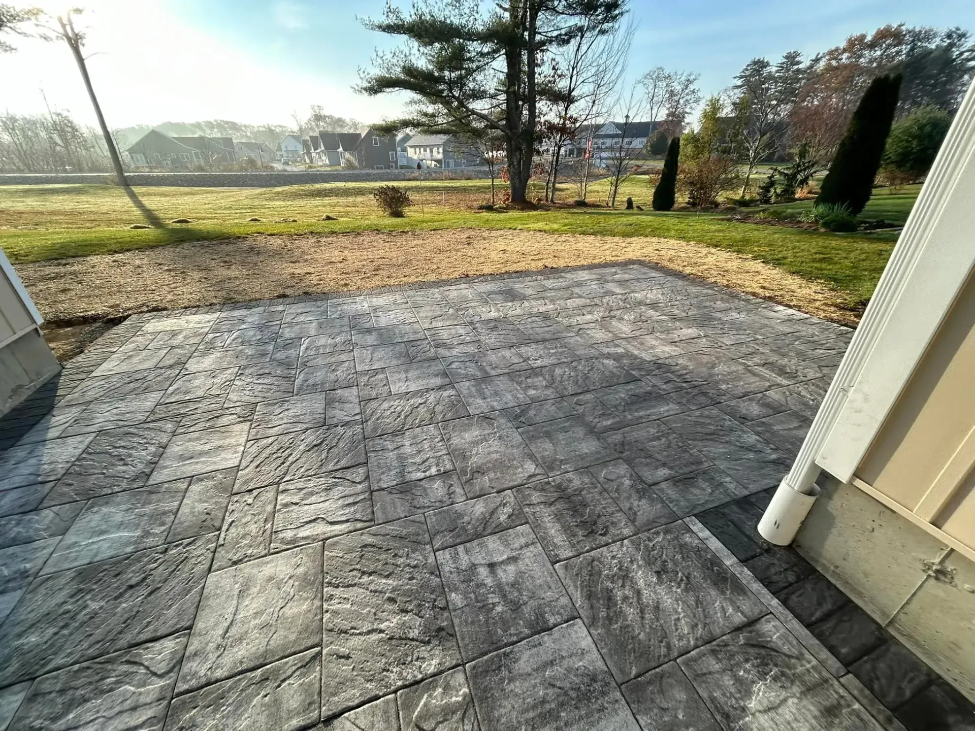 A patio with a view of a field and a house in the background.