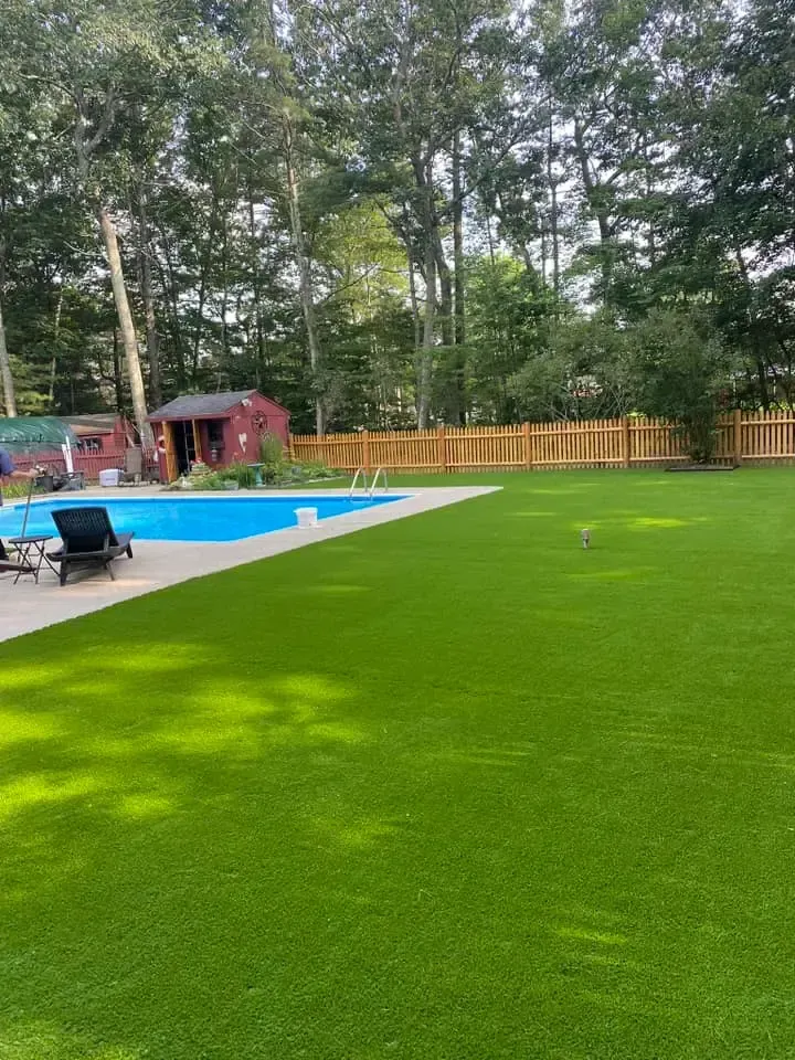 A large backyard with a swimming pool and a lush green lawn.