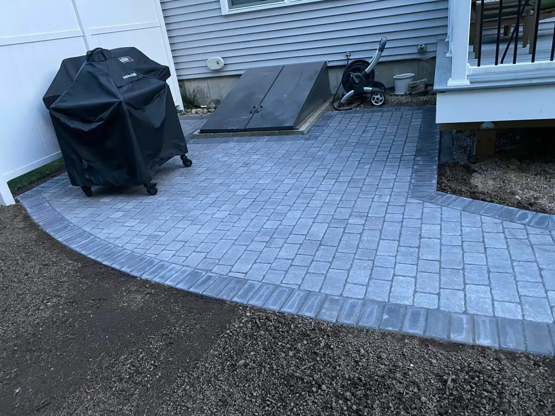 A patio with a grill and a ramp in front of a house.
