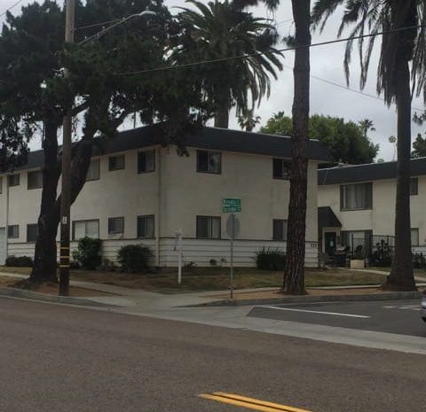 Street running next to apartment buildings and palm trees