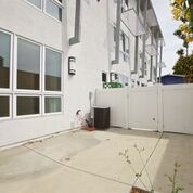 Concrete patio area with fence and a gate next to an apartment building