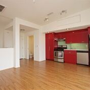 Apartment kitchen with stainless steel appliances and red cabinets; hardwood flooring
