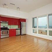 Apartment kitchen with stainless steel appliances and red cabinets; hardwood flooring and windows