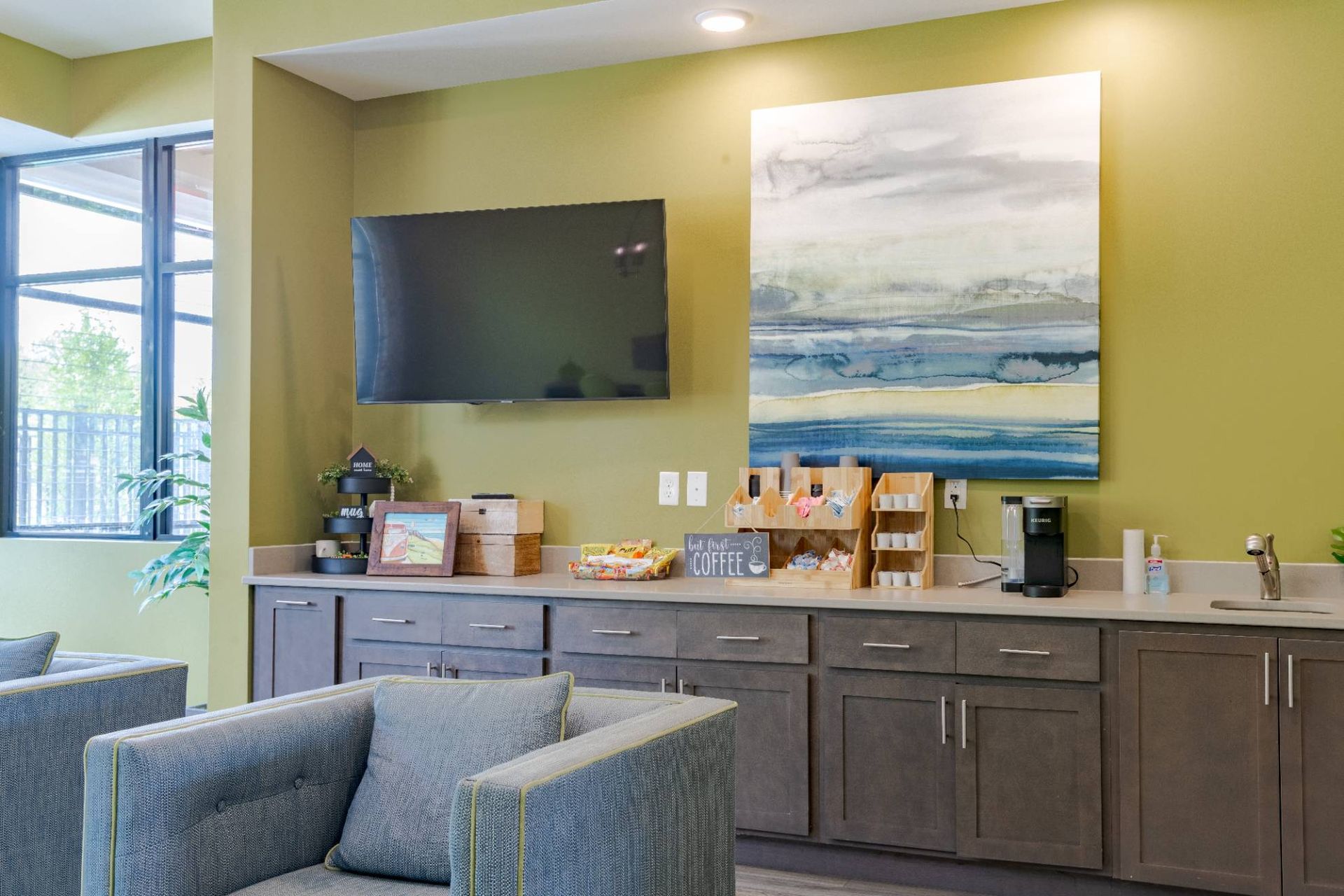 Community lounge with a wall-mounted TV, coffee station, and seating.