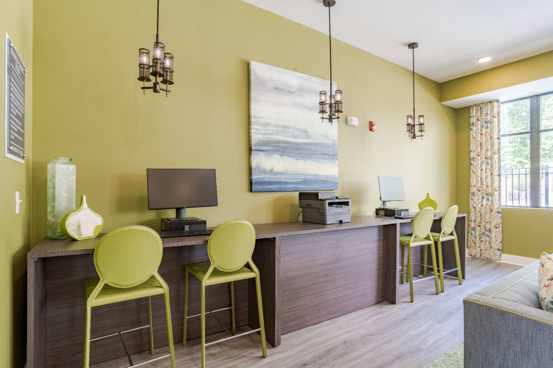 Community computer station with lime-green chairs, long desk, printer, and wall art.