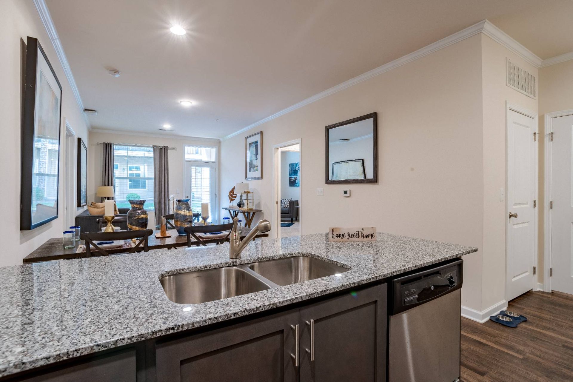 Open-concept kitchen with granite countertop and double sink, looking into the living area.