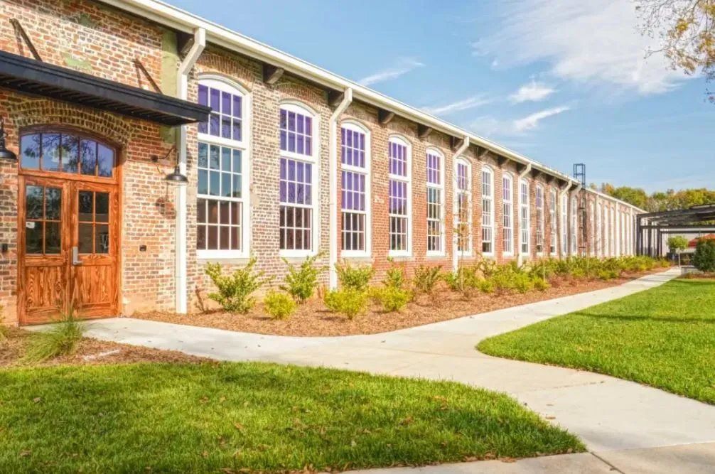 Exterior view of a brick building with large windows and landscaped pathway