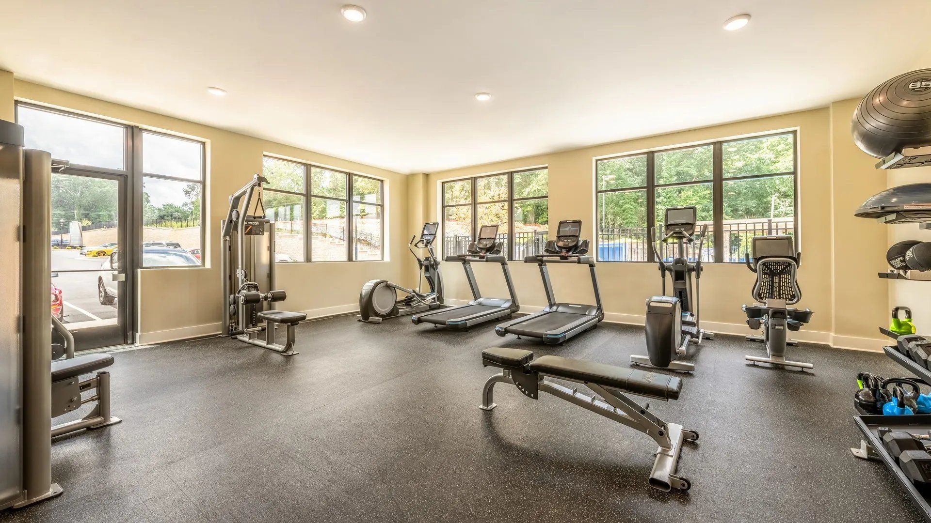 Bright and open gym area with various exercise equipment and large windows