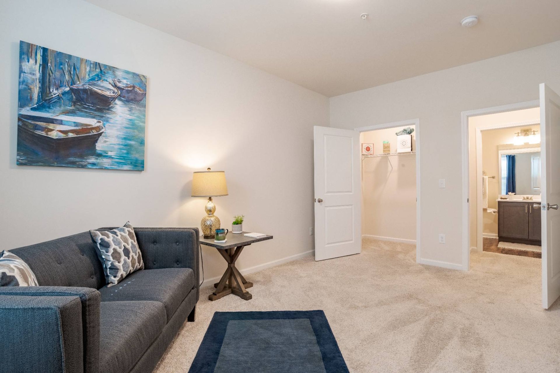 Living room in an apartment with gray sofa, side table, lamp, and wall art.