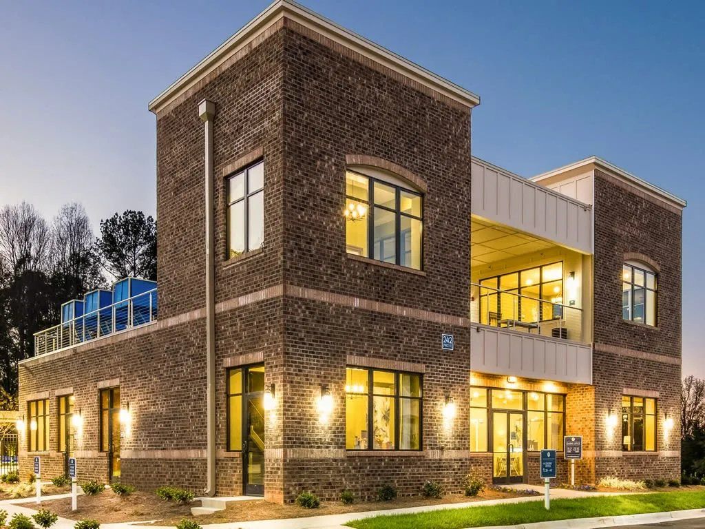 Exterior view of a modern brick building with large windows and a second-floor balcony