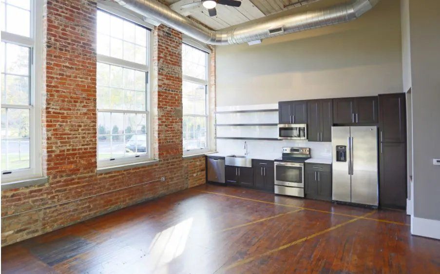 Spacious apartment kitchen with large windows and brick walls