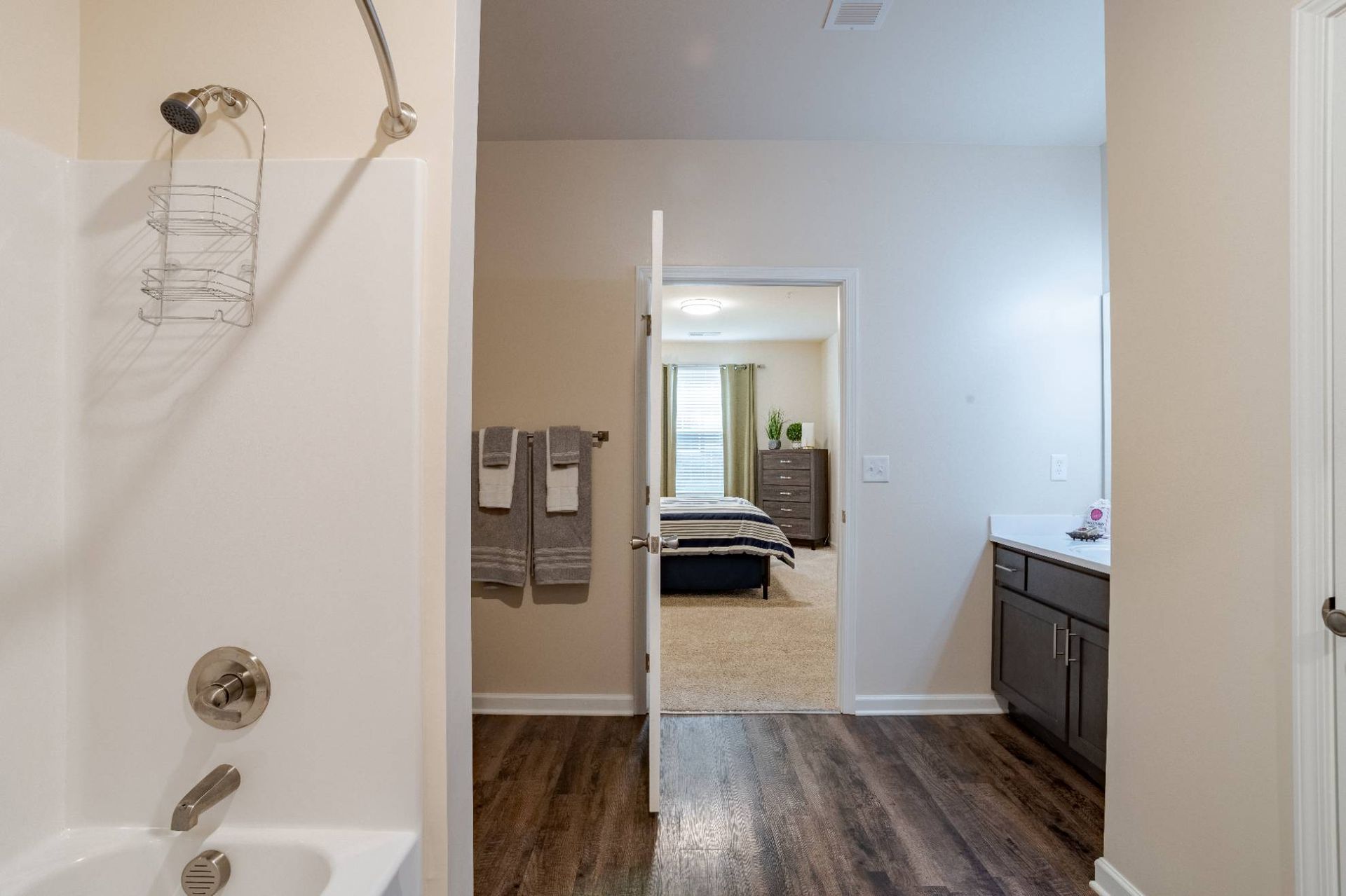 Bathroom with tub/shower on the left and doorway to a bedroom visible in the background.