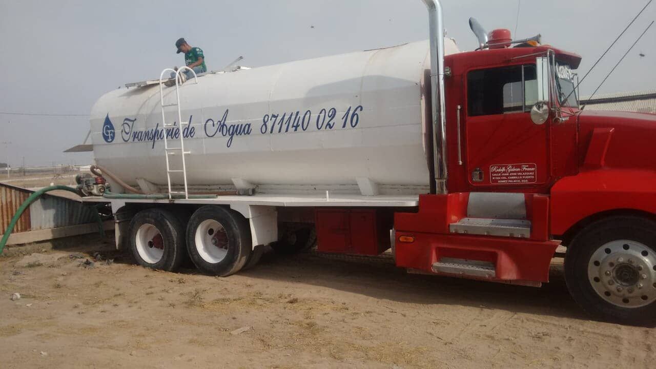 Un camión rojo y blanco está estacionado en la tierra.
