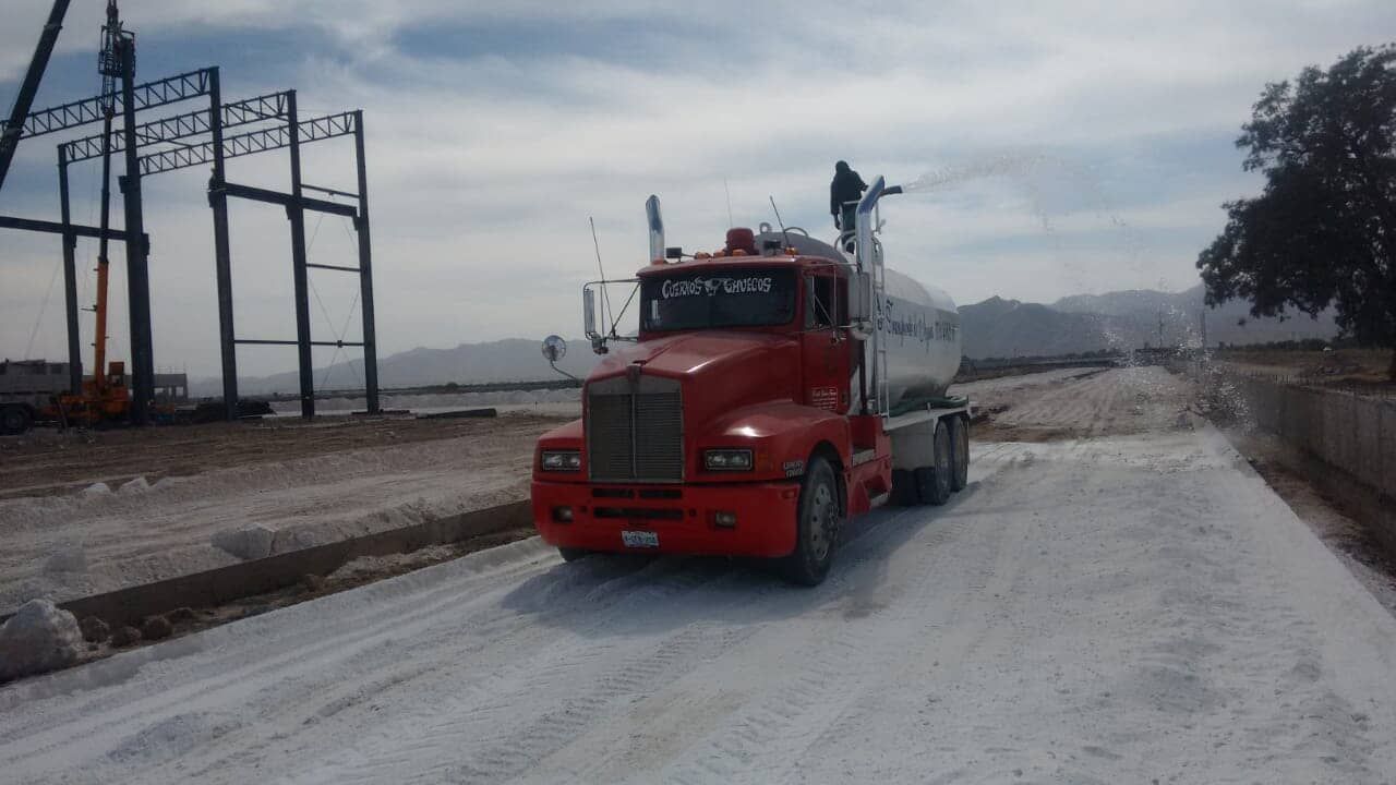 Un camión rojo circula por una carretera nevada.
