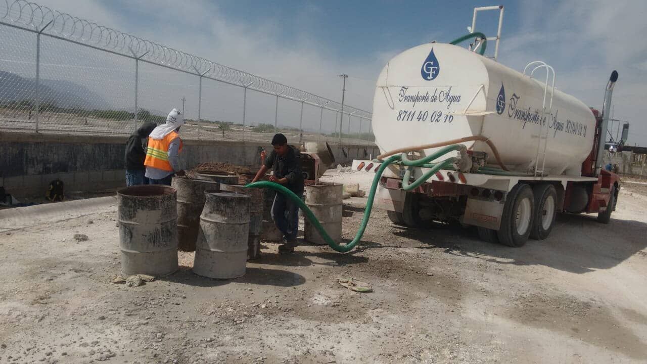 Un grupo de hombres bombea agua desde un camión cisterna.