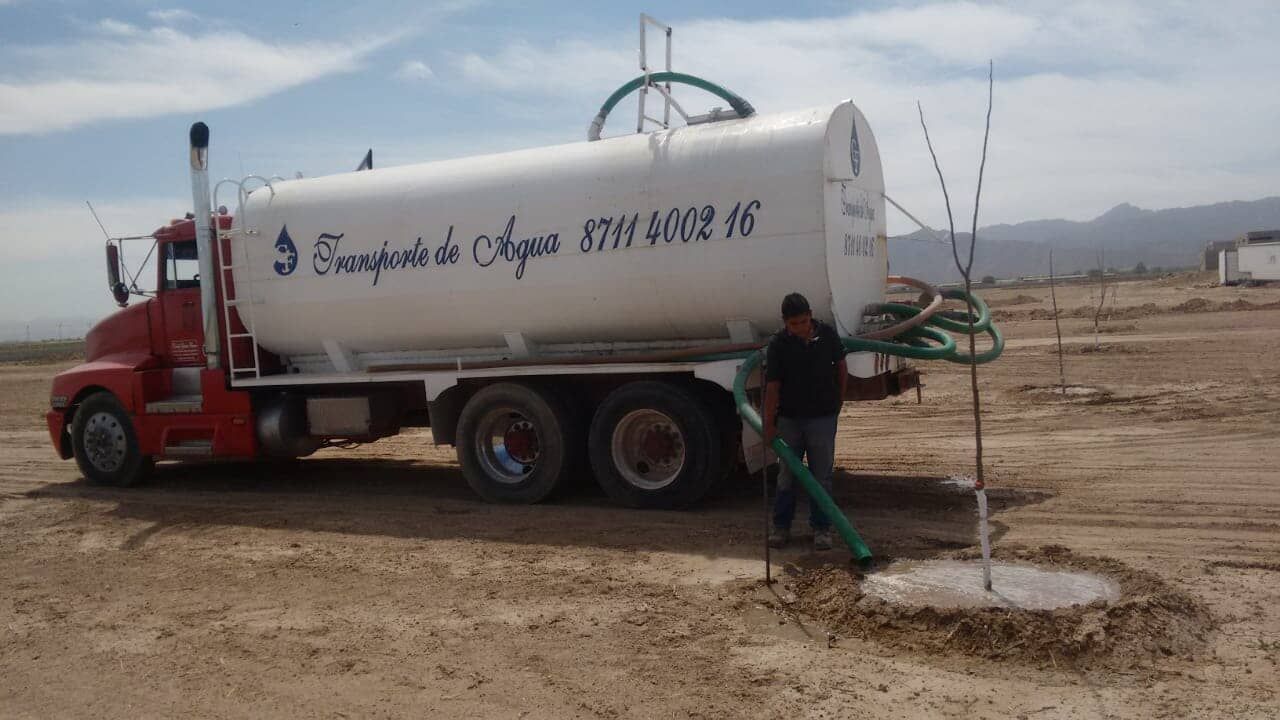 Un hombre está bombeando agua desde un camión cisterna