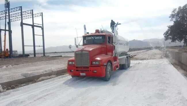 Un camión rojo circula por una carretera nevada.