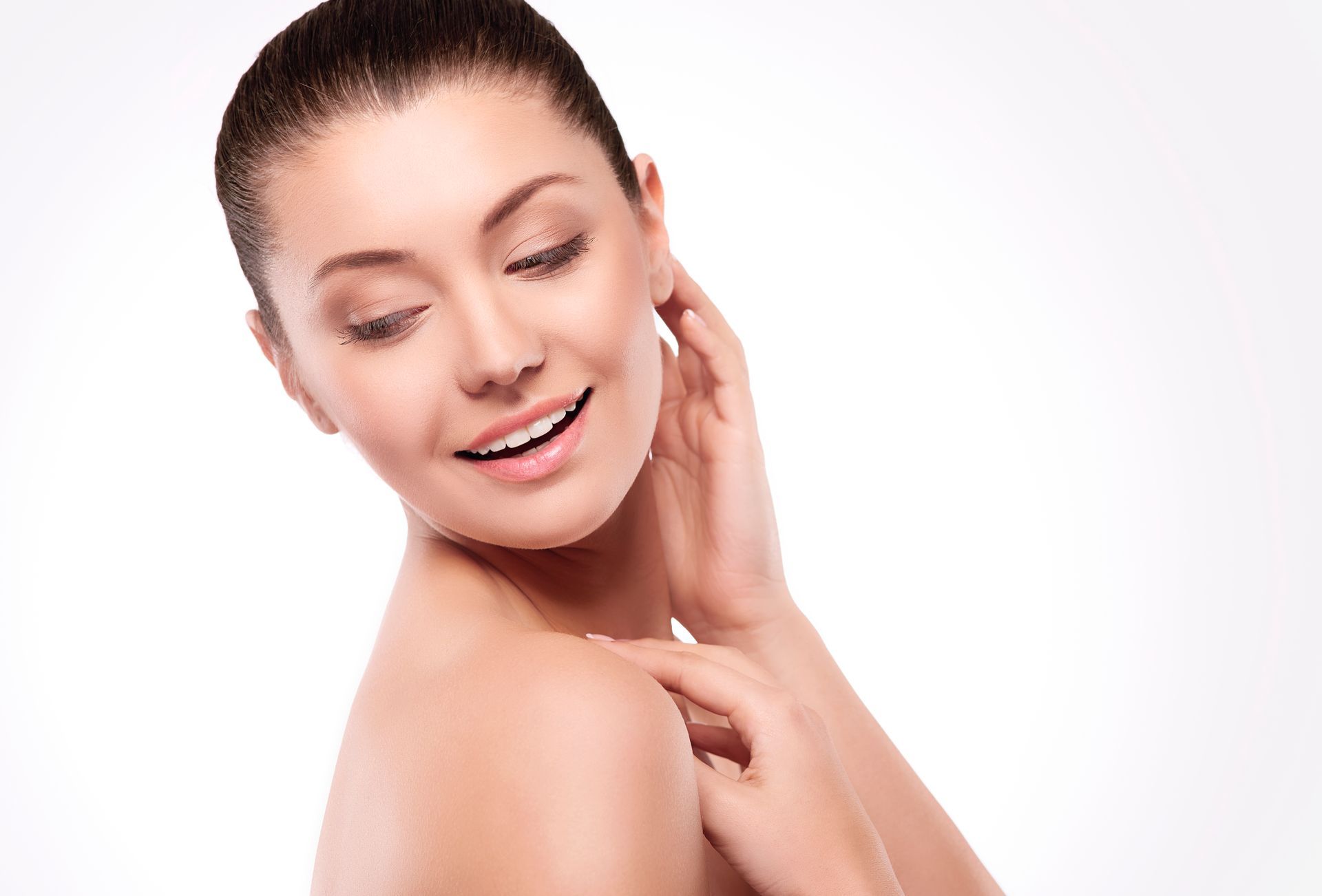 A woman is touching her face with her hand and smiling.
