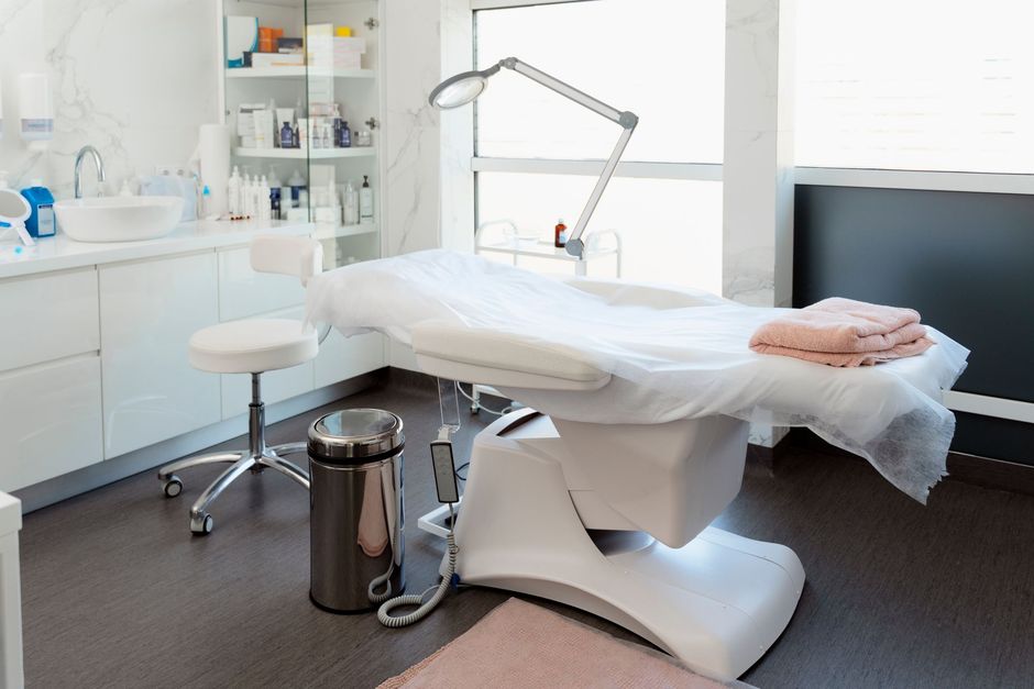 A medical room with a bed and a trash can.