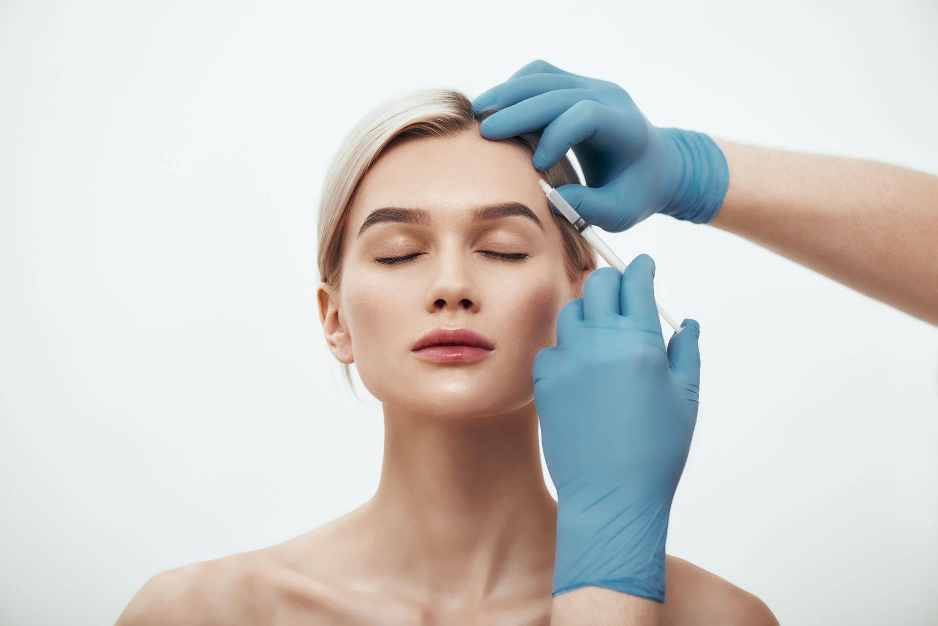 A woman is getting a botox injection in her forehead.