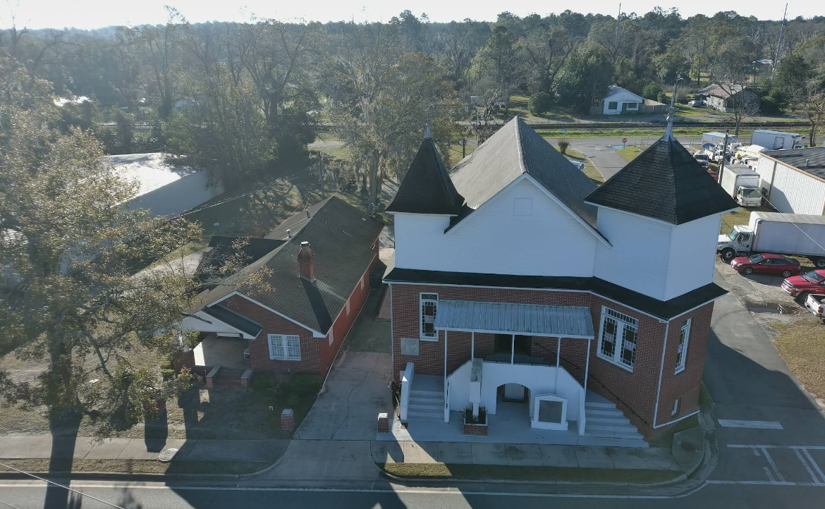 Red brick and white building with turrets, near waterfront and trees.