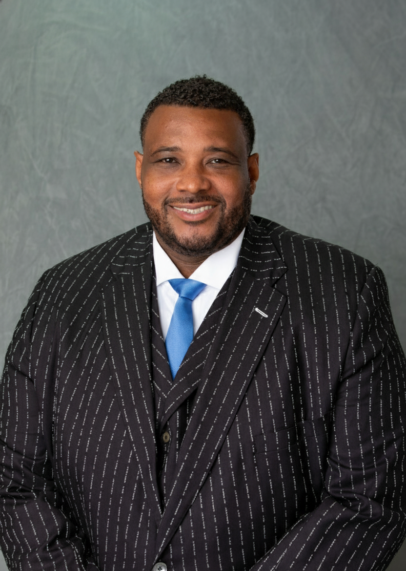 A man in a suit and tie is standing in front of a blue background.