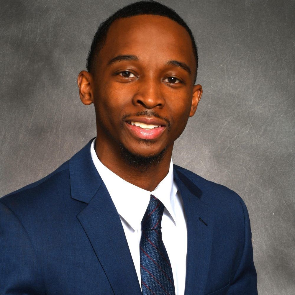 A man in a suit and tie is smiling for the camera