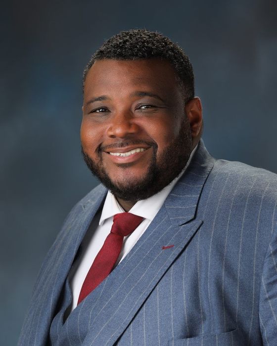 A man in a suit and tie is smiling for the camera.
