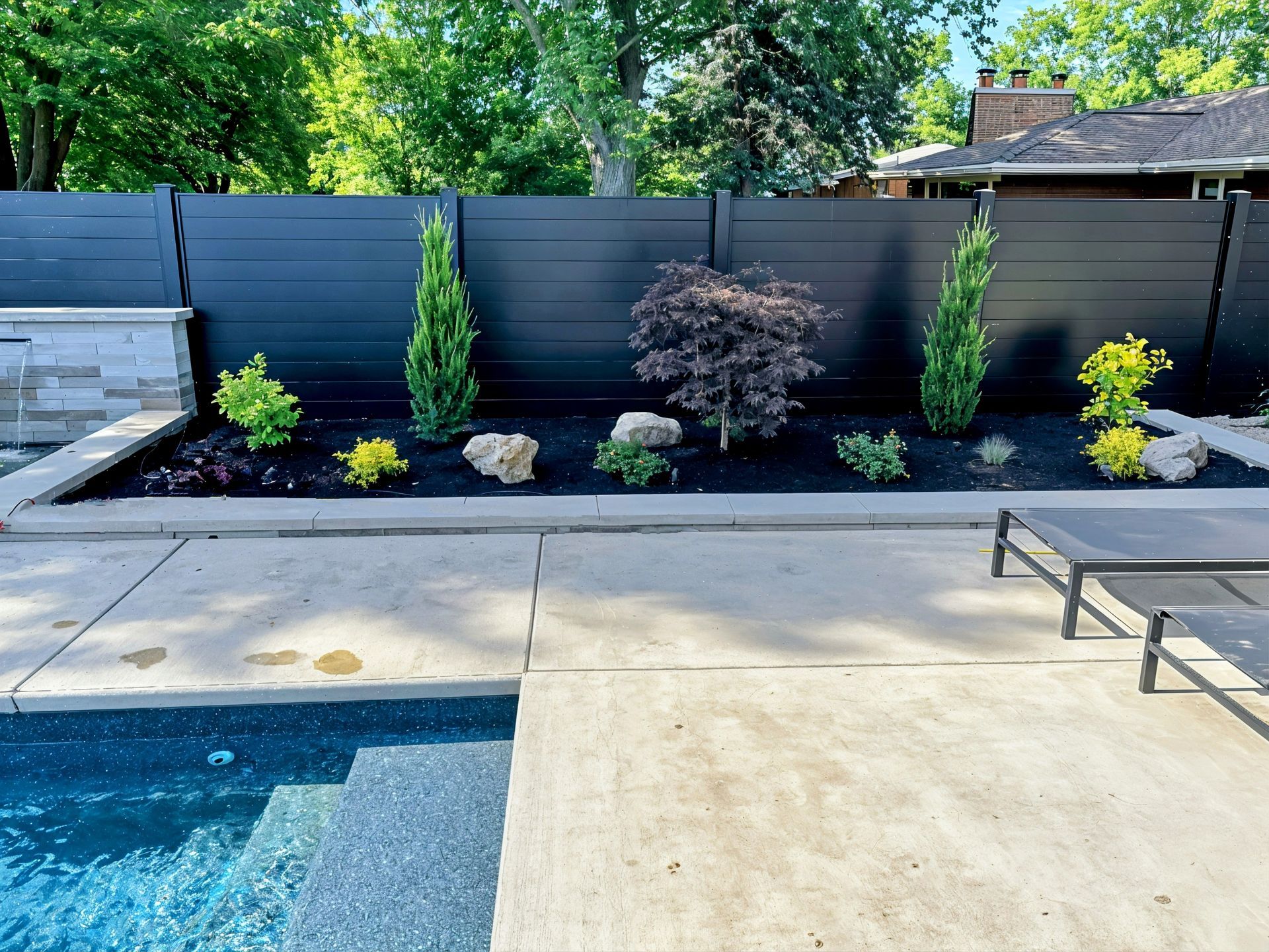 There is a swimming pool in the backyard with a black fence surrounding it.