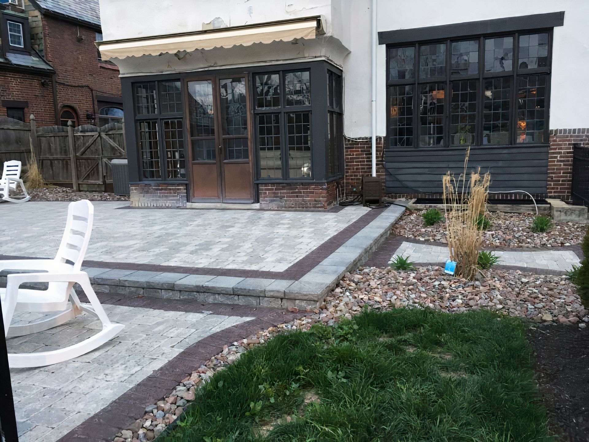 A white rocking chair is sitting on a patio in front of a house.