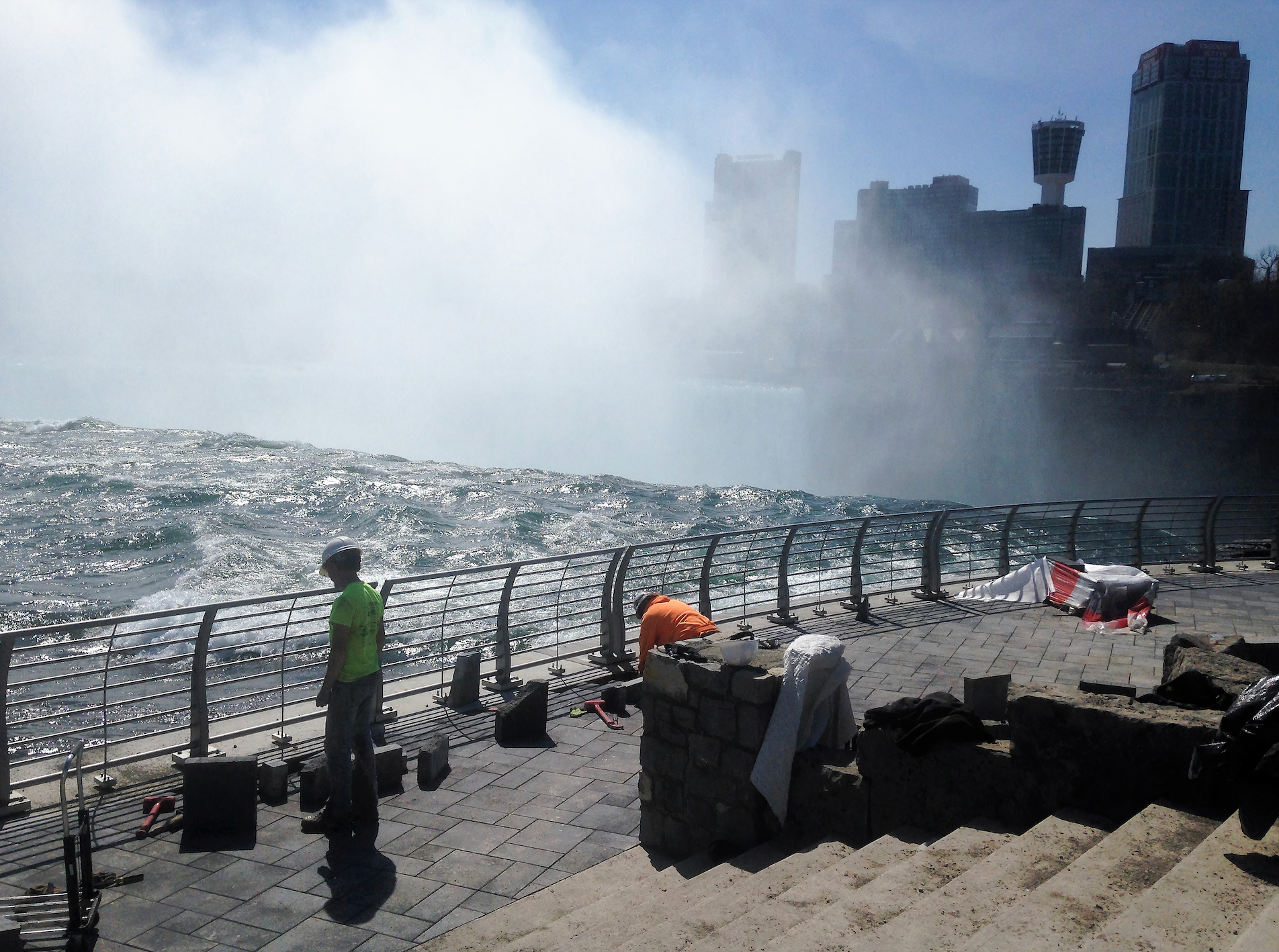 A man in a green shirt stands on a pier overlooking a body of water