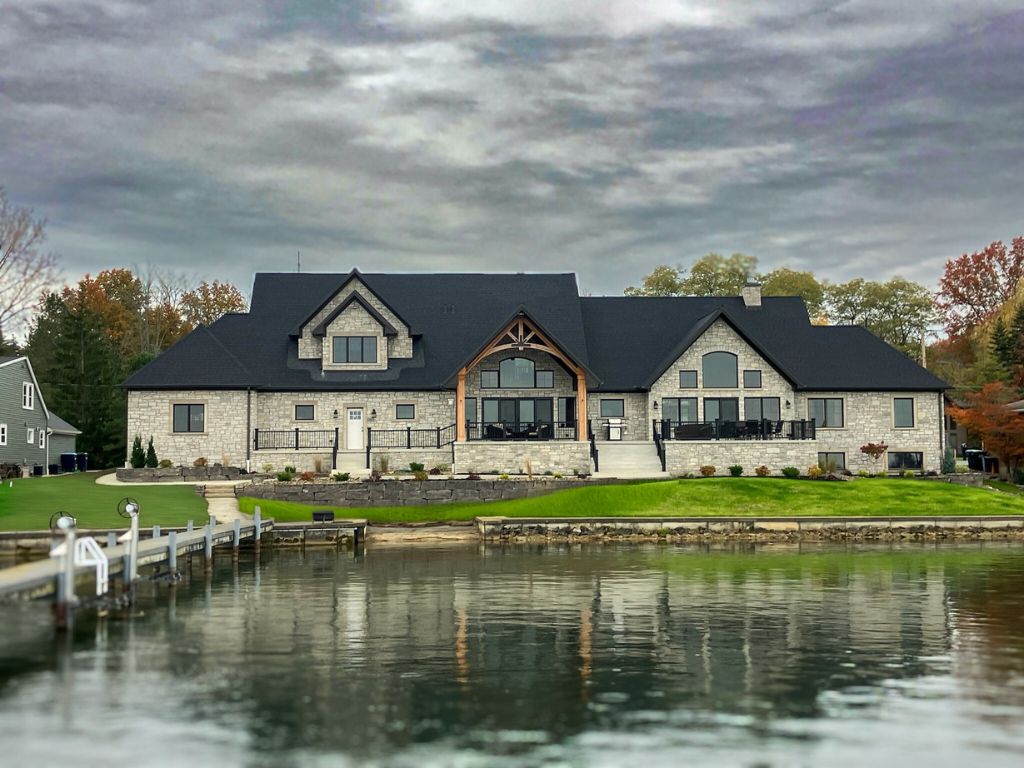 A large house sits next to a body of water.
