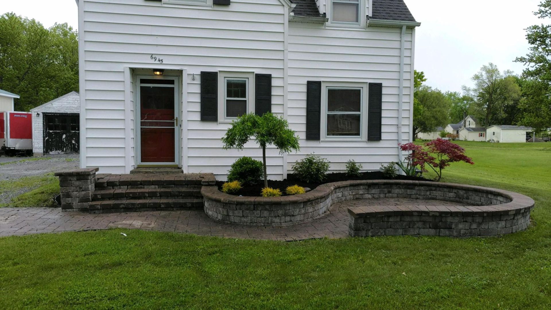 A white house with a brick planter in front of it.
