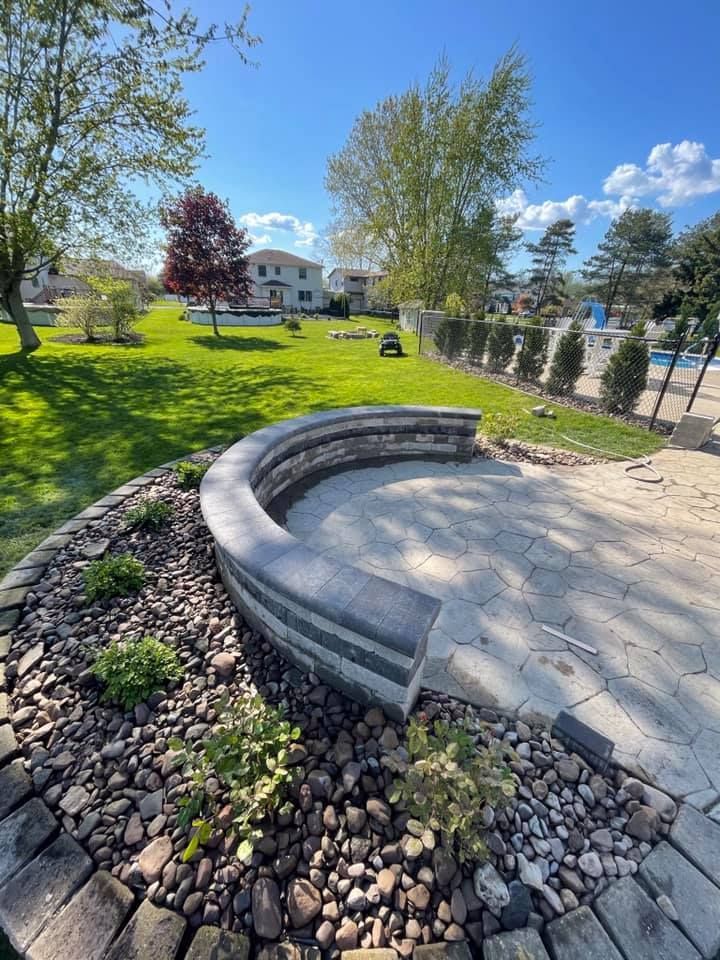 A curved stone wall is surrounded by rocks in a park.