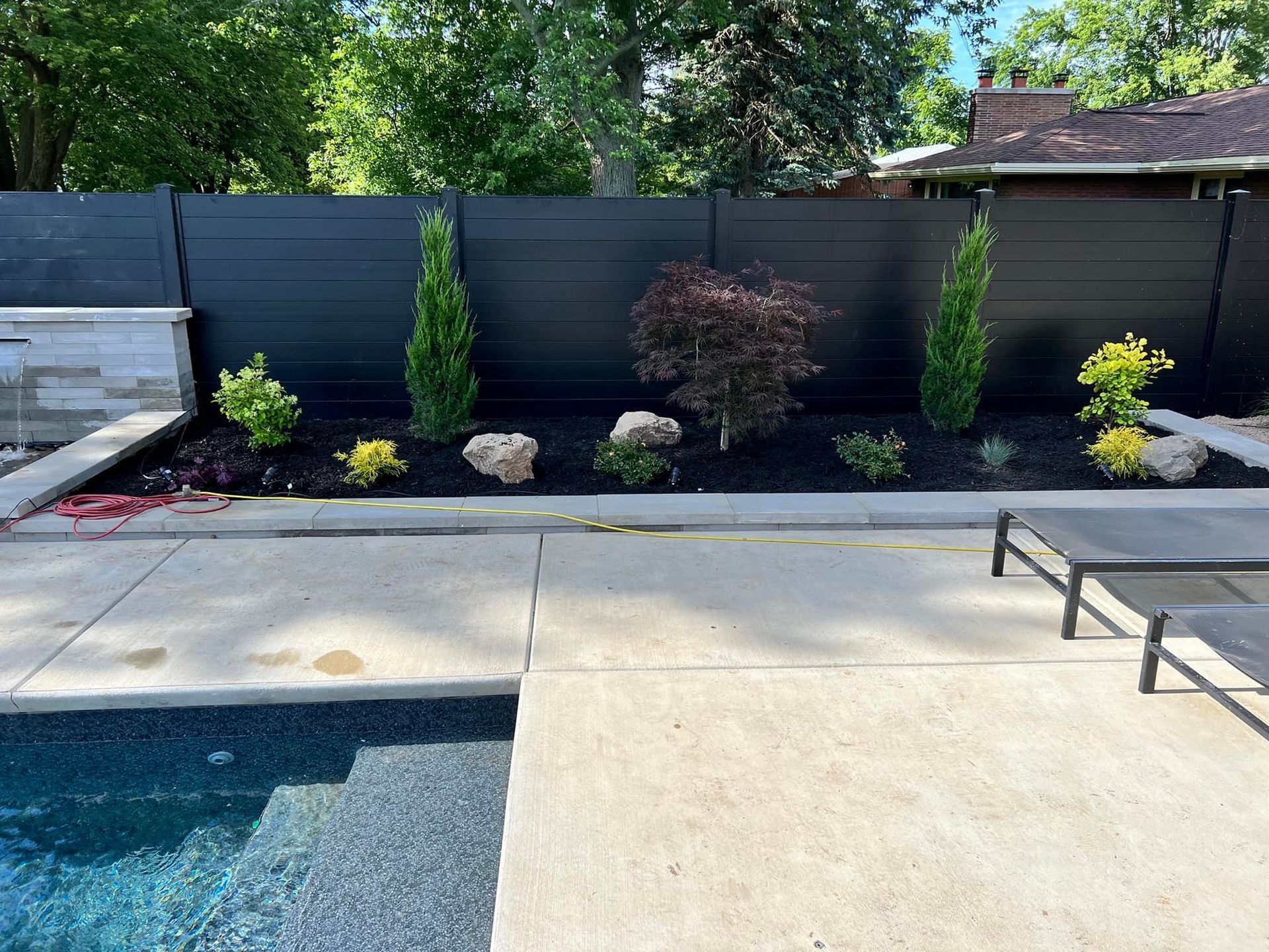 There is a swimming pool in the backyard with a black fence surrounding it.