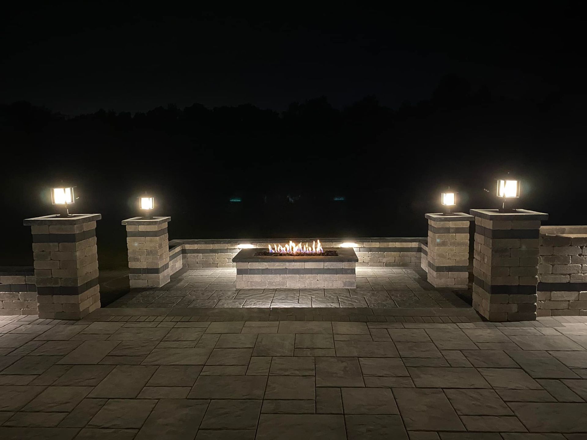 A fire pit is lit up at night on a patio.