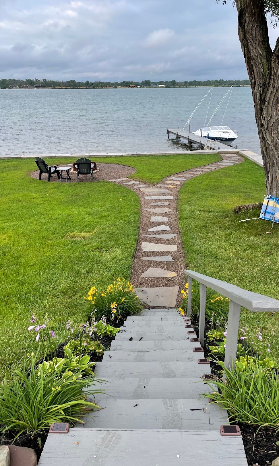 A stone walkway leading to a dock with a boat in the water.