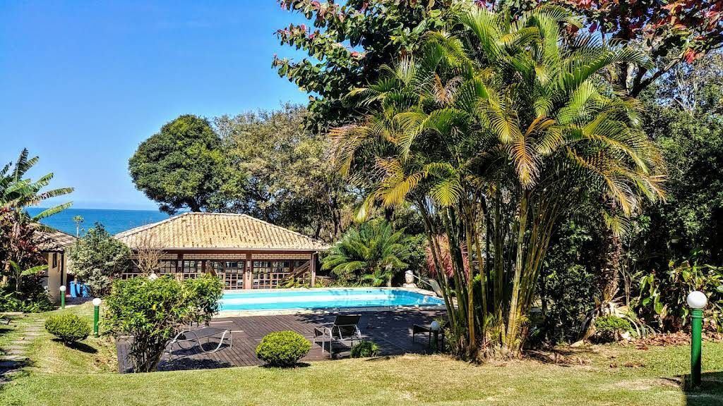 Vista aérea de um resort com telhados vermelhos, piscina, estacionamento e arredores verdes.