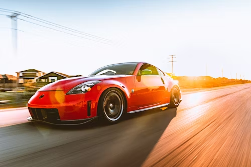 A red sports car is driving down a road.