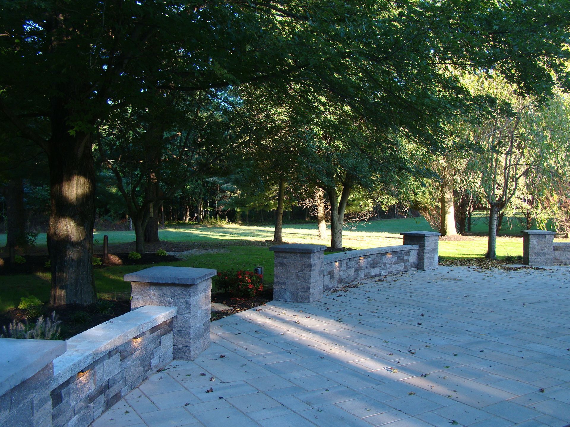 A patio with a stone wall and trees in the background