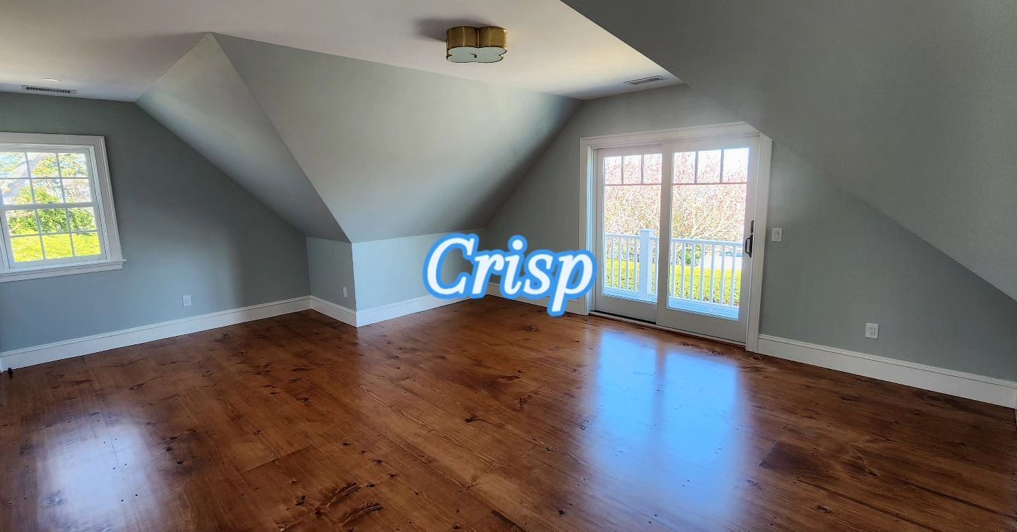 Empty attic-style room with sloped ceiling, hardwood floors, two windows, and blue carpet near one window.