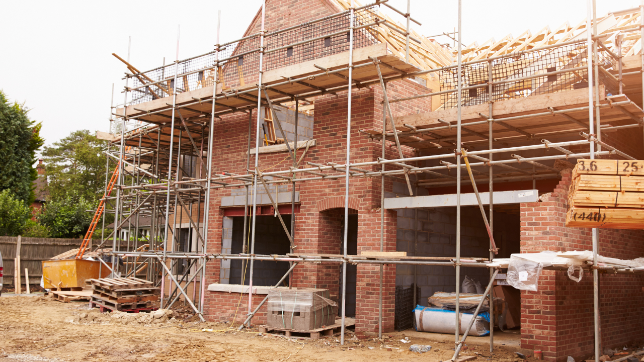 Brick house under construction; scaffolding surrounds building.