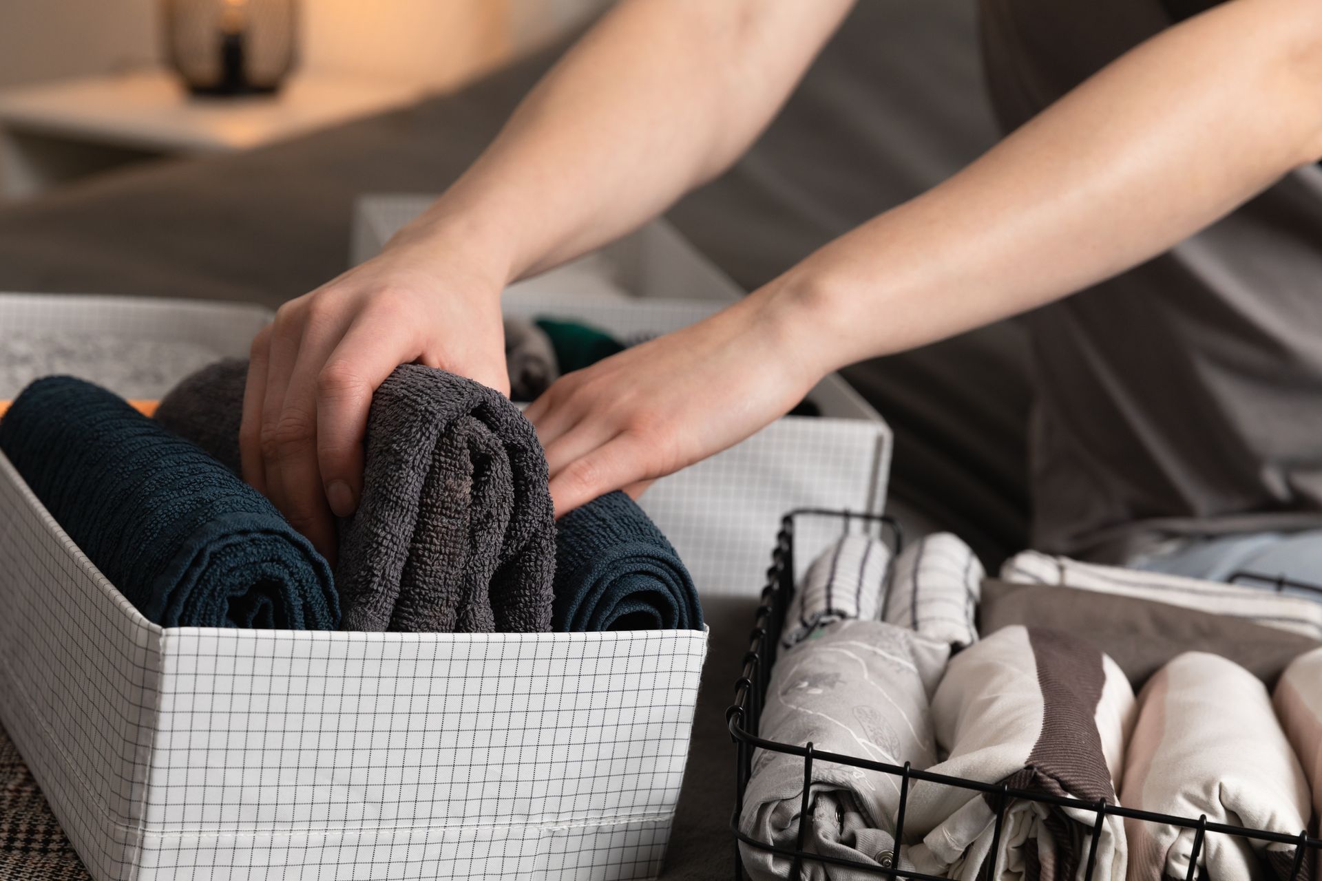Person folding towels into storage bins on a bed.