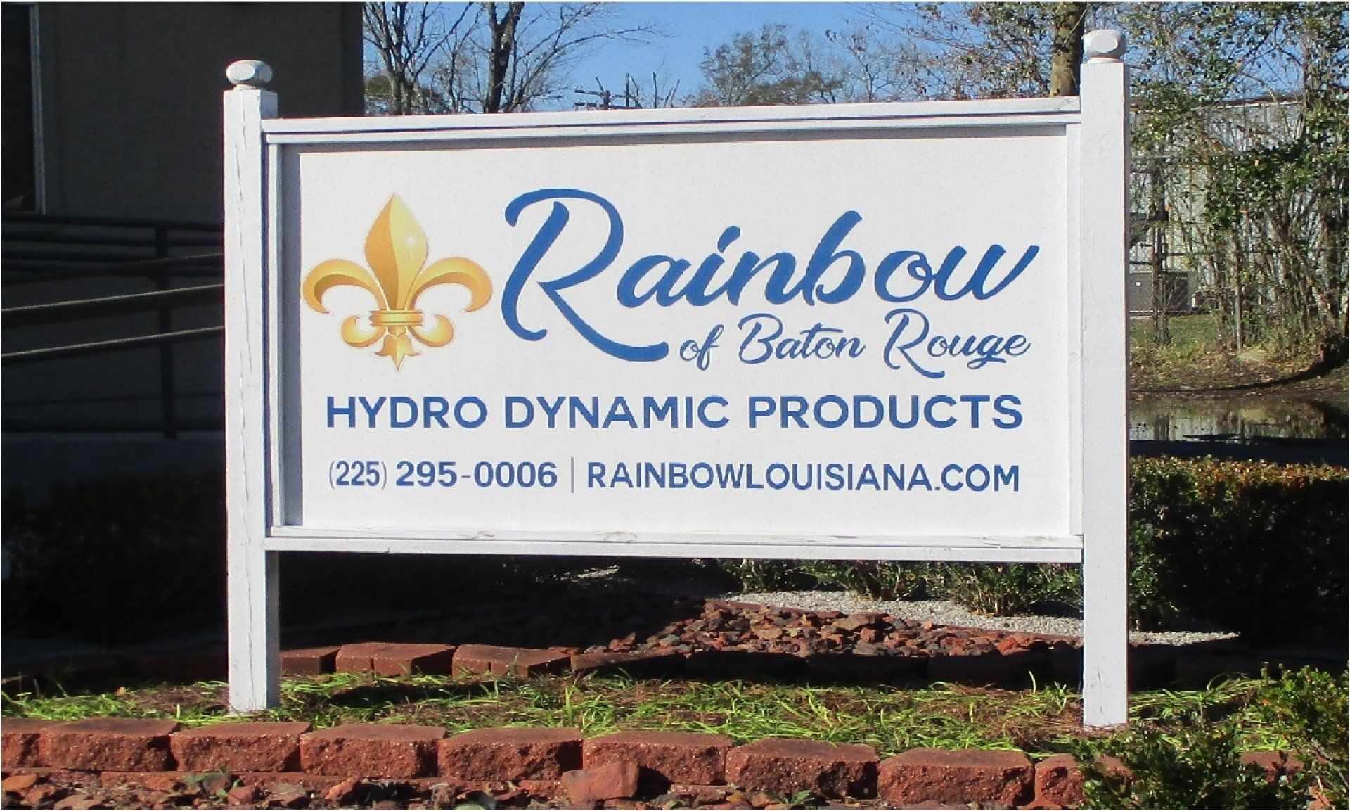Sign for Rainbow of Baton Rouge, a hydro dynamic products company. Features a fleur-de-lis and the company's name, phone number, and website.