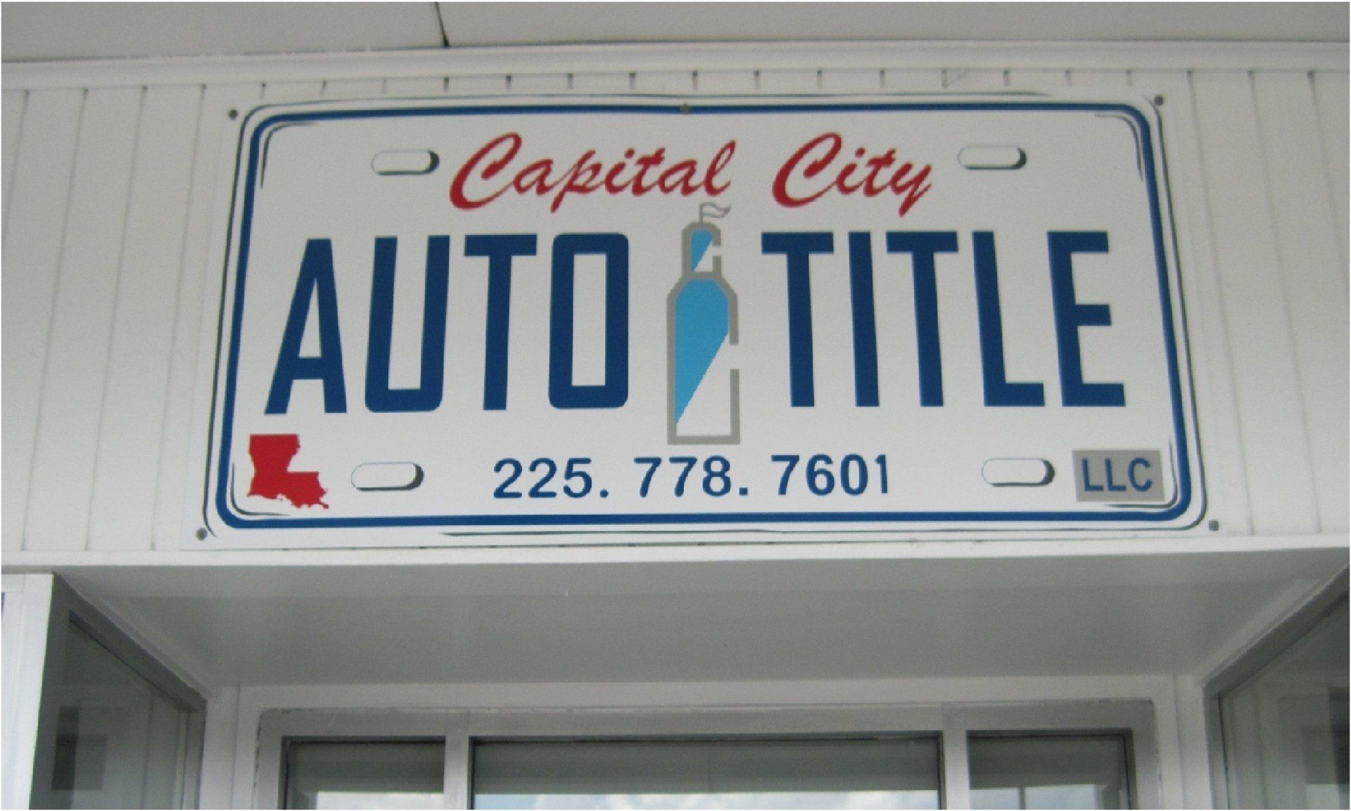 Sign for Capital City Auto Title, featuring a license plate design. Includes phone number and Louisiana outline.
