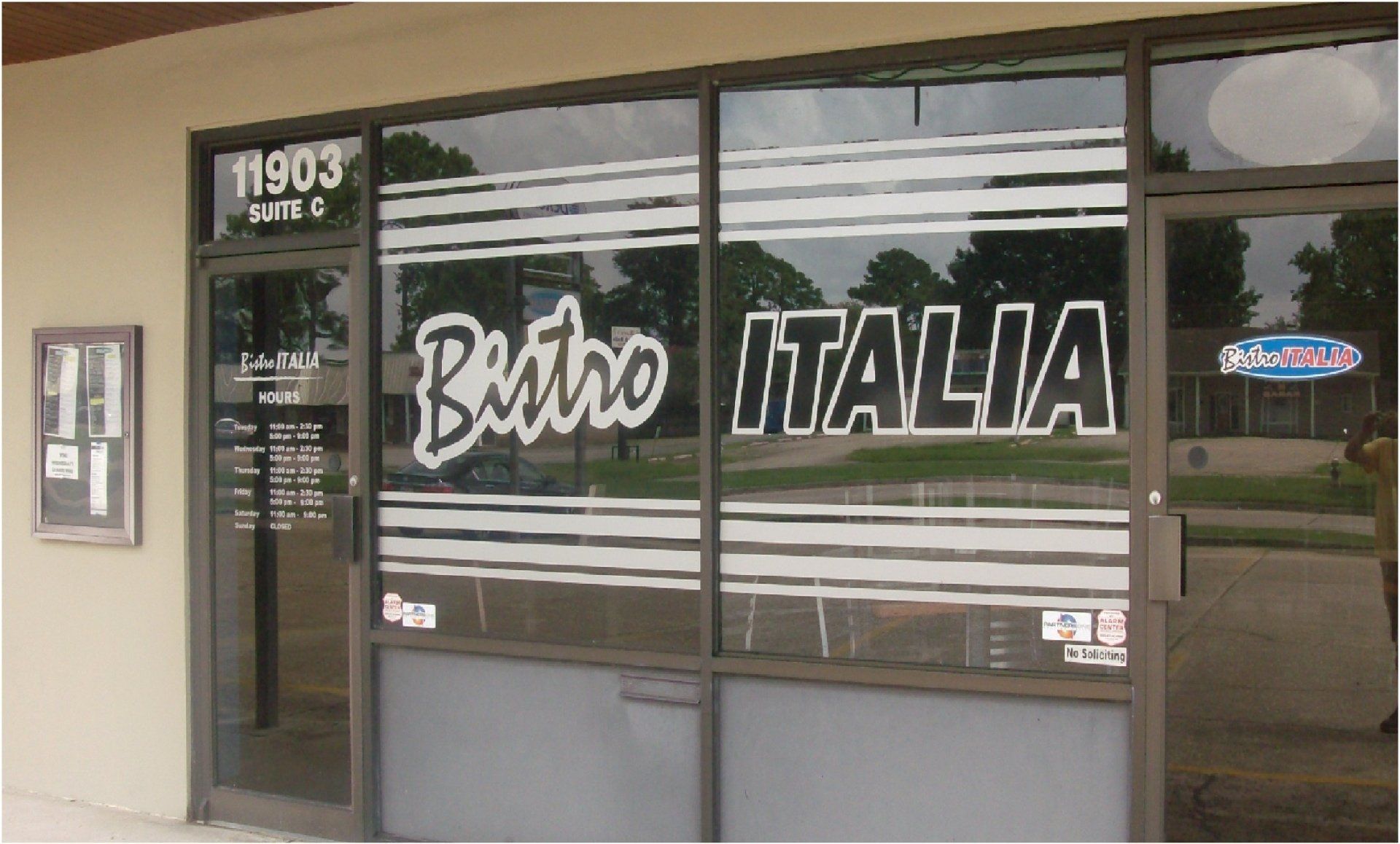Exterior of Bistro Italia restaurant with large windows, black lettering, and address 